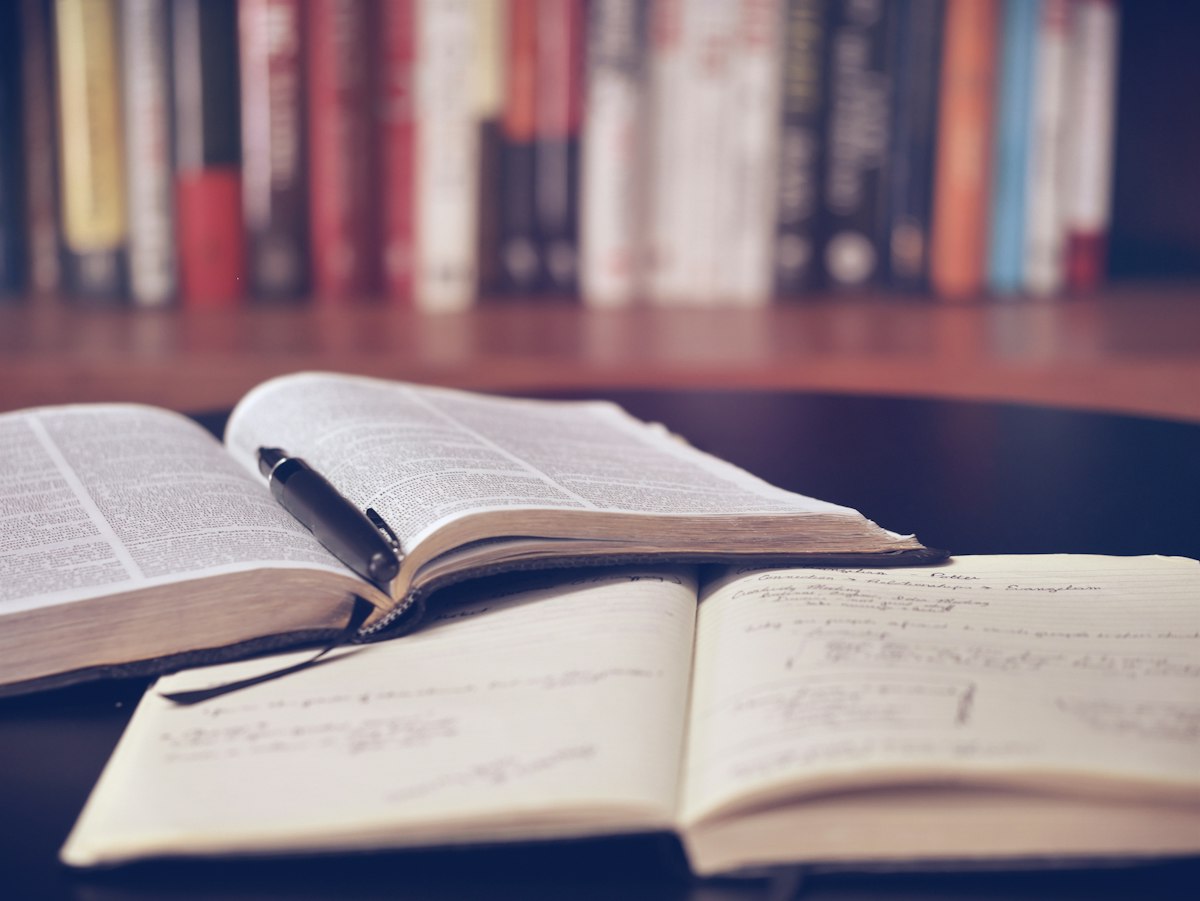 Open notebook and pencil on a wooden desk, suggesting study and reflection
